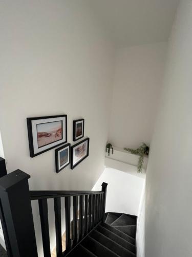 a hallway with white walls and stairs with pictures on the wall at Modern 2 bedroom beach house in Cleethorpes