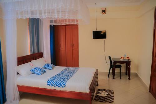 a bedroom with a bed and a table with a television at Jatheo Hotel Rwentondo in Mbarara