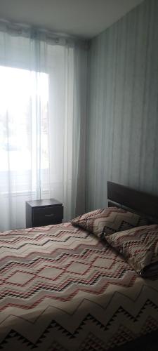 - une chambre avec un lit avec une couverture rayée et une fenêtre dans l'établissement Le Rosier, à Lure