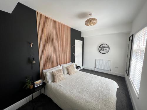 a bedroom with a white bed and a black wall at Modern 2 bedroom beach house in Cleethorpes