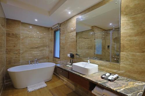 Punarnava Resort & Spa في دهرادون: حمام مع حوض ومغسلة ومرآة