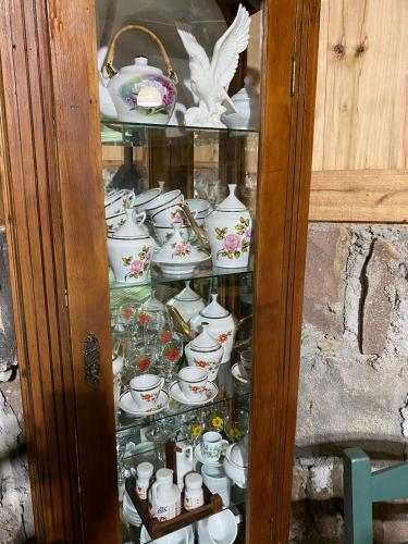 a glass cabinet filled with cups and teapots at Casarão Biazolli in Farroupilha