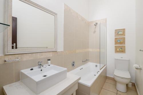 een badkamer met een wastafel, een toilet en een spiegel bij San Lameer Villa 3008 - 4 Bedroom Classic - 8 pax - San Lameer Rental Agency in Southbroom