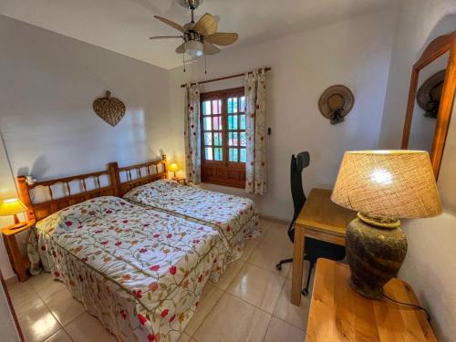 ein Schlafzimmer mit einem Bett und einem Tisch mit einer Lampe in der Unterkunft Puertito Varadero in Puerto de Santiago