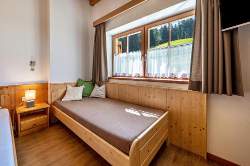 a bed in a room with a window at Urthalerhof Apt Landhaus in Valdaora
