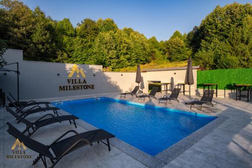 a pool with chairs and umbrellas in front of a building at Villa Milestone Majevica 