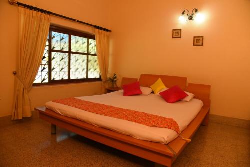 Un dormitorio con una cama con almohadas rojas y una ventana en Coffee Tranquil Homestay - Private Water Falls & Premium Experience, en Chikmagalur