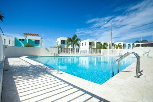 a swimming pool with blue water and white buildings at Modern Beach Walk at Puerto Bahia #30 in Rincon