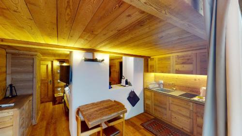 una cucina con soffitto in legno e tavolo in legno di Abitaziun Güglia - Silvaplana a Silvaplana