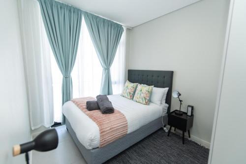 een slaapkamer met een bed met blauwe gordijnen en een raam bij Bella Retreat Bellamare in Summerstrand