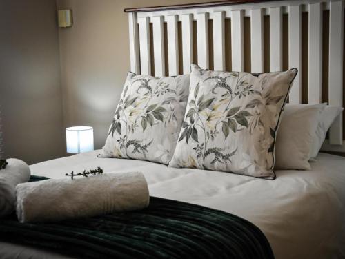 a bed with white sheets and pillows on it at River Olive Estate Accommodation in Beaufort West