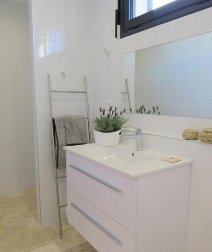 une salle de bain blanche avec un lavabo et un miroir dans l'établissement Superbe Villa T5 Luxe- Piscine chauffée privée -face MER 8ERTAR7, au Barcarès