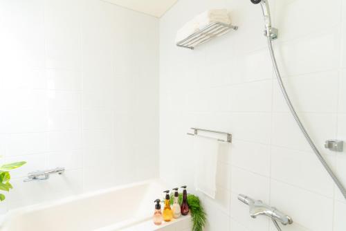 a bathroom with a shower and a tub with bottles on a shelf at Comfort Villa YAGAJI in Nago
