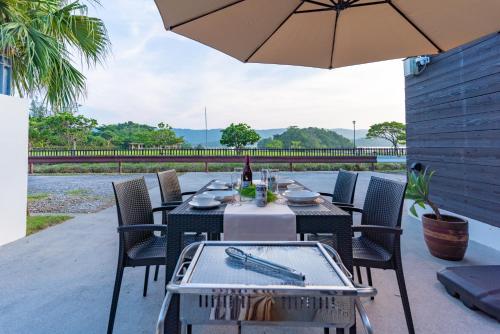 a table with chairs and an umbrella on a patio at Comfort Villa YAGAJI in Nago