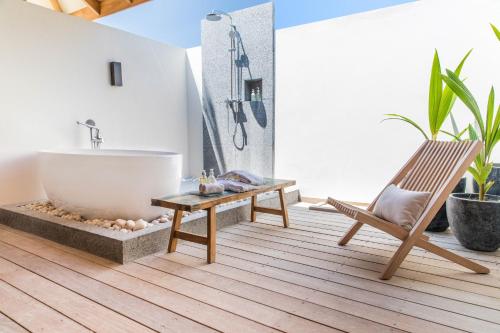 a bathroom with a tub and a chair and a bath tub at Kagi Maldives Resort & Spa in North Male Atoll