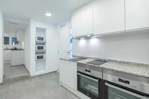 cocina con armarios blancos y encimera en Residencia Universitaria Trinitarios en Valencia