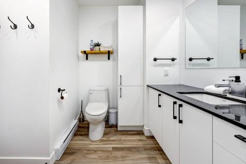 a white bathroom with a toilet and a sink at Panorama Penthouse- piscine, gym et vue sur Québec in Quebec City
