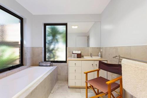 a bathroom with a tub and a chair and a sink at Coastal meets Country at this Ventnor Beach Escape in Ventnor