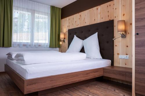 a bedroom with a large white bed with a wooden headboard at Residence Lex in Resia