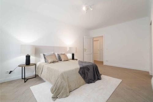 a white bedroom with a large bed and a table at Luxury Living First District in Vienna