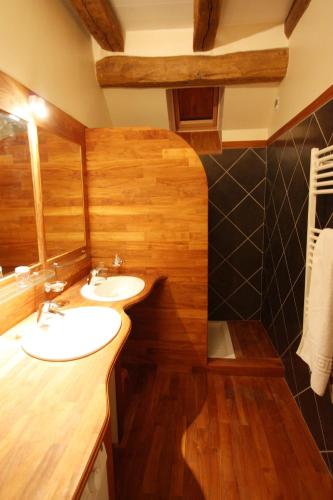 La salle de bains est pourvue de 2 lavabos et de murs en bois. dans l'établissement La Maison de Violette, à Baigneux-les-Juifs