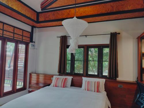 1 dormitorio con cama blanca y ventanas en Suntisook Resort, en Ko Yao Noi