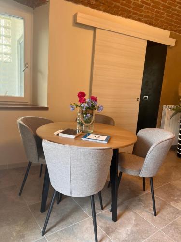 a dining room table with chairs and a vase of flowers on it at Le camere del Cappello Verde in Ivrea