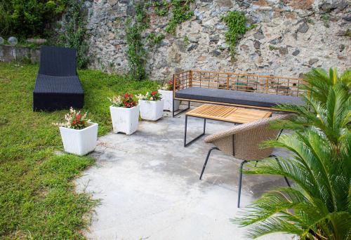 a patio with a bench and three potted plants at Le camere del Cappello Verde in Ivrea