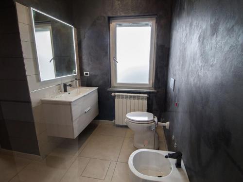 a bathroom with a sink and a toilet and a window at Le camere del Cappello Verde in Ivrea