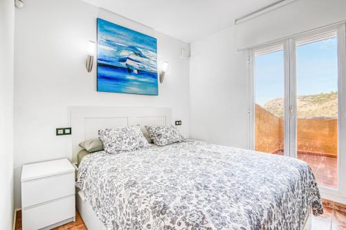 ein weißes Schlafzimmer mit einem Bett und einem Fenster in der Unterkunft La Cumbre in Benitatxell