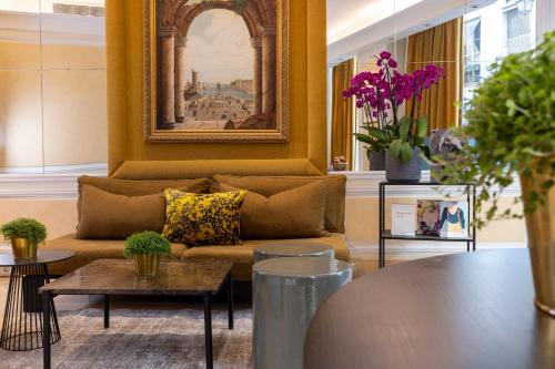 a living room with a couch and a painting on the wall at Hôtel Le Regent Paris in Paris