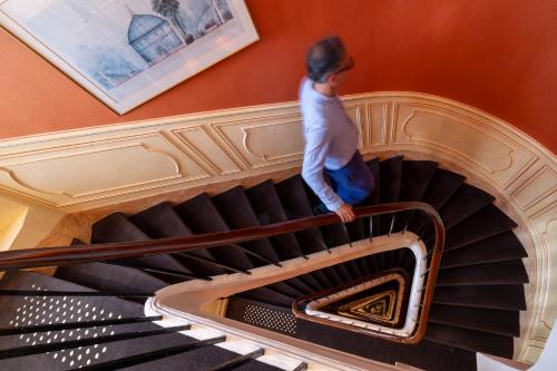 a woman walking up a spiral staircase at Hôtel Le Regent Paris in Paris