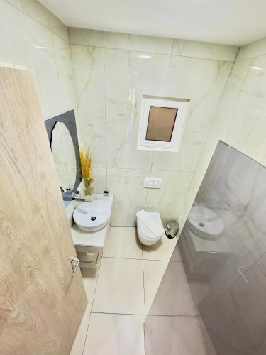 a white bathroom with two toilets and a sink at Villa Merkuri in Himare