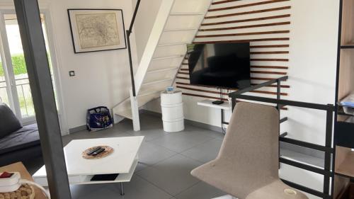 ein Wohnzimmer mit einer Treppe und einem TV in der Unterkunft JLGD in Monthyon