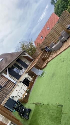 a house with a wooden deck and a green lawn at JLGD in Monthyon