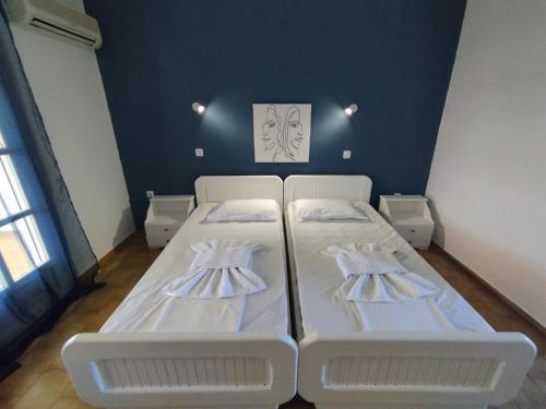 a bedroom with two white beds and a blue wall at Spasmata Apartments no cooking in Minia