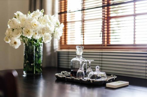 a table with a vase of white flowers and a bottle at Upington African Vineyard Boutique Hotel & SPA in Kanoneiland