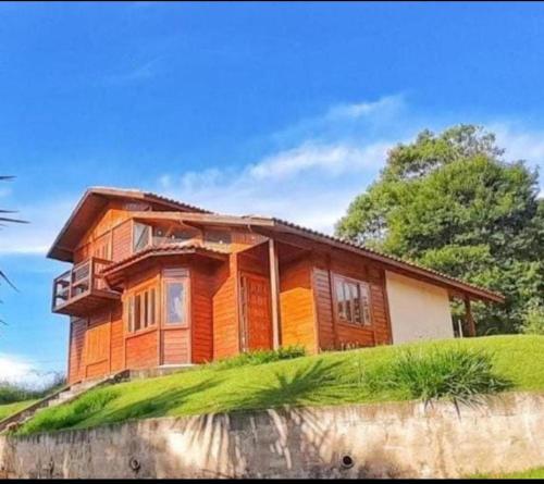 a wooden house on top of a grassy hill at Biju's Little Farm in Ibiúna