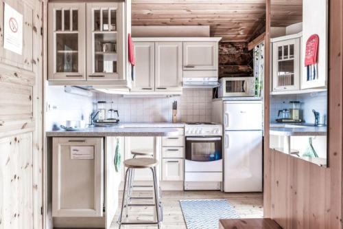 a small kitchen with white cabinets and a stool at Holiday Village Himmerki in Posio