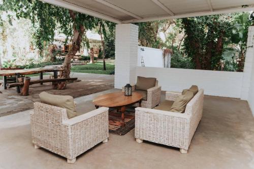 a patio with a wooden table and chairs and a table and a table at Upington African Vineyard Boutique Hotel & SPA in Kanoneiland
