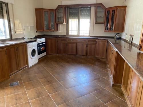 a kitchen with wooden cabinets and a tile floor at Full furnitured house بيت مفروش للأيجار in Sūf