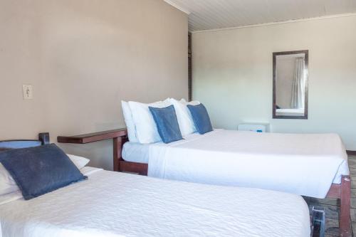 a hotel room with two beds and a mirror at Pousada dos Coqueiros Búzios in Búzios
