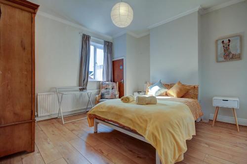 a bedroom with a bed with a yellow blanket on it at Fliss's House in Leicester