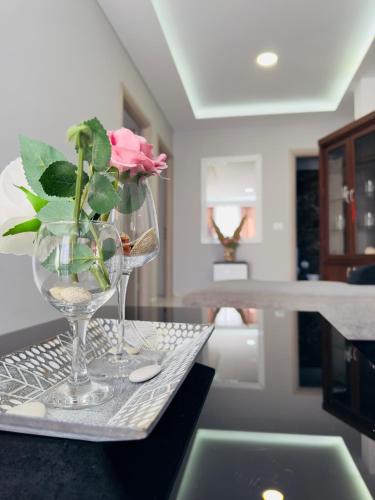 a table with two wine glasses and a pink rose at Villa Merkuri in Himare