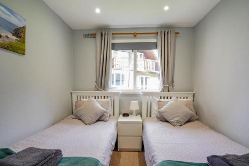 two beds in a small room with a window at Cornish Holiday - 91 Hengar Manor in Saint Tudy