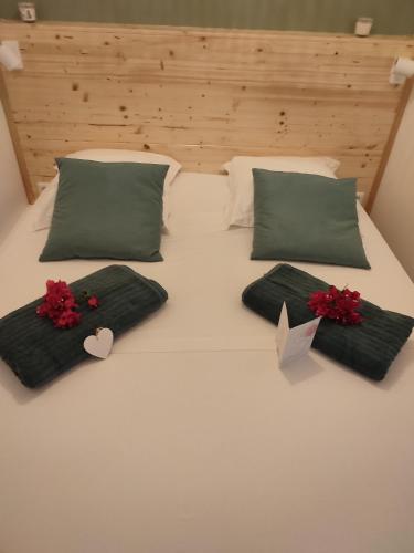 a white bed with green pillows and red flowers on it at Appartement SERENITE, tout confort 2adultes 1 enft in Les Trois-Îlets