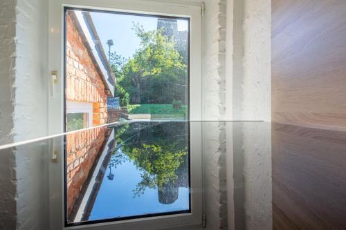 a window with a reflection of a tree in the water at Eglise 26 Aparthotels in La-Roche-en-Ardenne