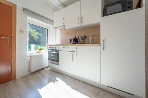 a kitchen with white cabinets and a large window at Eglise 26 Aparthotels in La-Roche-en-Ardenne