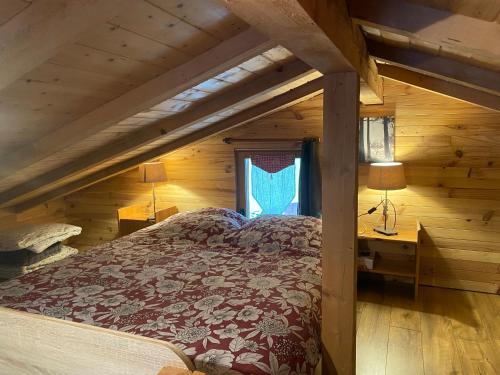 ein Schlafzimmer mit einem Bett in einer Holzhütte in der Unterkunft Gîte Croc Blanc in Sondernach