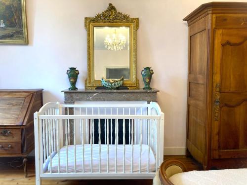 - un lit bébé dans une chambre avec un miroir et une commode dans l'établissement Château Fontclaire, à Pons